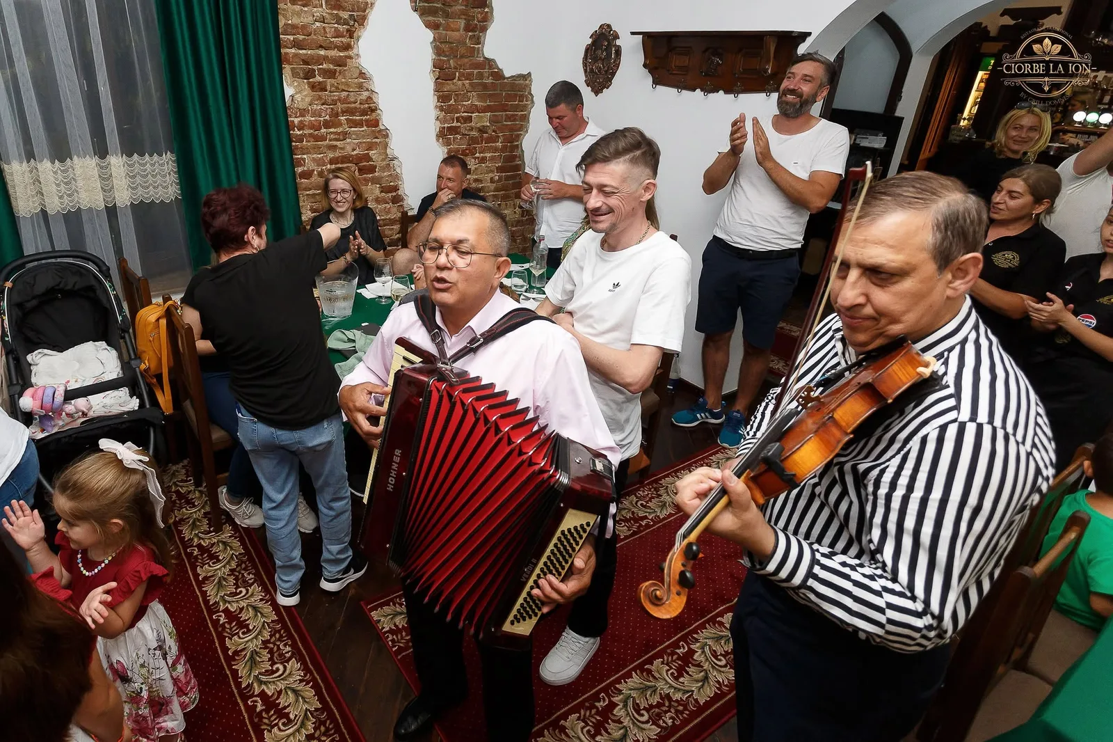 Familii și lăutari în salonul restaurantului Ciorbe La Ion