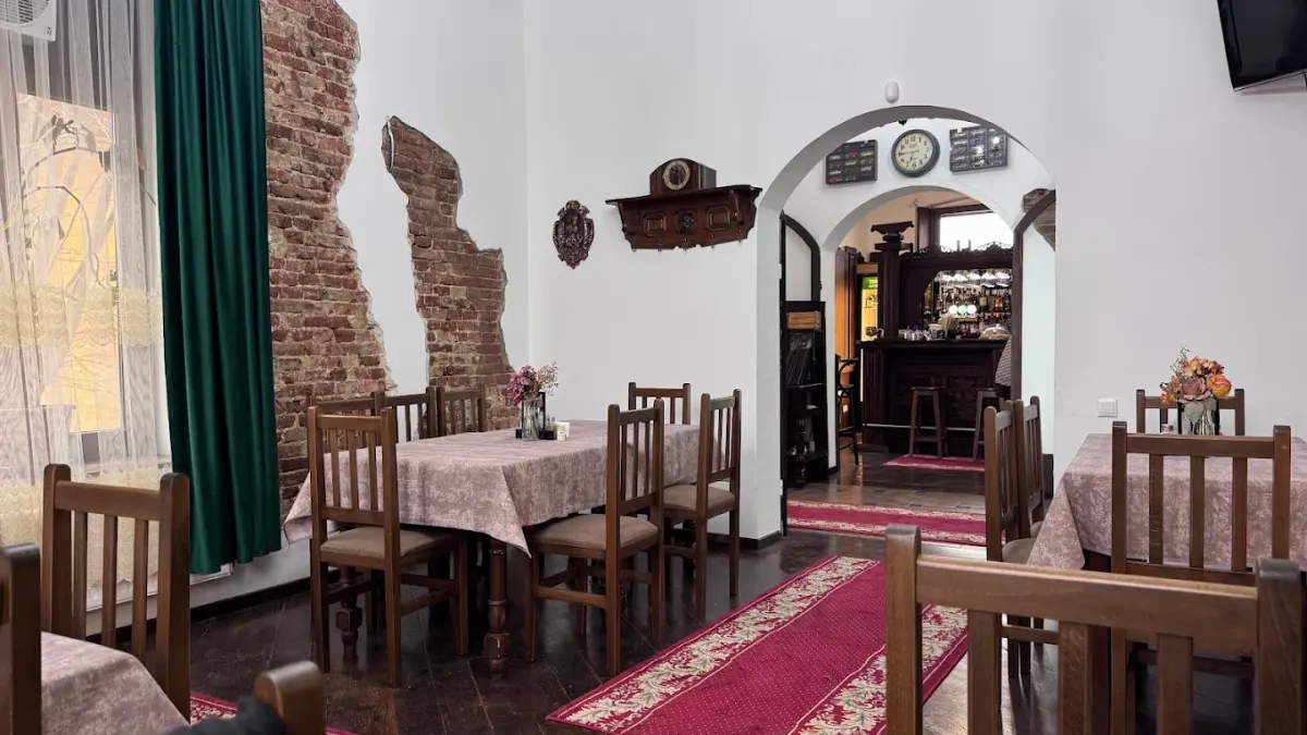 Salonul restaurantului, cu mesele pregătite și barul văzut prin arcadă